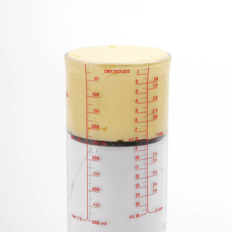 Two Cup Adjustable Measuring Cup With Grippy Rotating Body For Easy Pouring Of Peanut Butter And Honey filled with butter