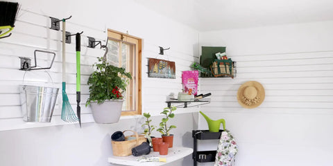 Garage with organized white SlatWall featuring tools, plants, and storage, showcasing Hands On Sample Ring With Wall And Ceiling Board Trim.
