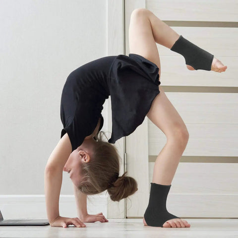 Child in yoga pose wearing Youth Ankle Compression Sleeve For Active Kids Knit Ankle Brace For Sprains Tendonitis And Arthritis Perfect For Basketball Running Soccer Dance And Fitness Non Slip Secure Fit Breathable Sock Style 1 Pair Black