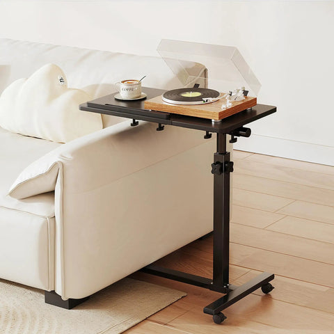 Must-Have Adjustable Overbed Table With 180-Degree Swivel Desktop beside a couch, holding a record player and cup, black finish