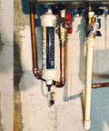 CondensateRx condensate neutralizer, white cylindrical unit installed on copper piping under boiler