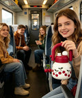 Person holding cherry-themed jug with red handle on train.