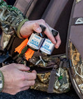 Person holding Double Scent Drag Deer Urine Kit For Scrapes And Ambush Hunts Buck And Doe Lure bottles with backpack.