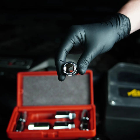 Gloved hand holding socket tool from 8 Piece Stud Extractor Set For SAE And Metric, Broken Stud Removal Sockets, Stud Puller Kit For Automotive Repairs, Versatile Tool To Remove Rusted, Stripped And Broken Studs, with red carrying case in background.