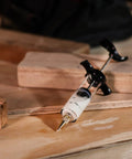 Slick Precision Wood Glue Syringe With Replaceable Tips For Tight Joints Offers Smooth High Pressure Application Holds Twenty Milliliters Capacity on wooden surface.