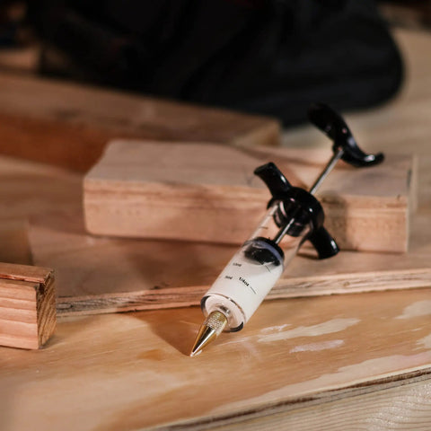 Slick Precision Wood Glue Syringe With Replaceable Tips For Tight Joints Offers Smooth High Pressure Application Holds Twenty Milliliters Capacity on wooden surface.
