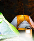 Workhorse 20W Led Portable Work Light And Solar Flood Illuminator with tents at night, providing bright illumination outdoors.