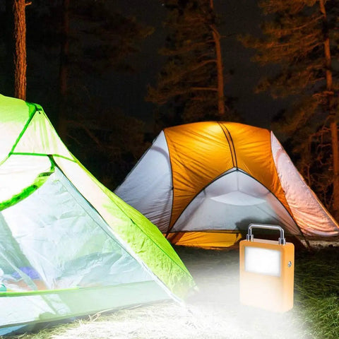Workhorse 20W Led Portable Work Light And Solar Flood Illuminator with tents at night, providing bright illumination outdoors.