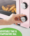 Hand adjusting Pink Mini Oven With Healthy Ceramic Nonstick Coating, Compact Countertop Bake Broil Toast Pizza Maker