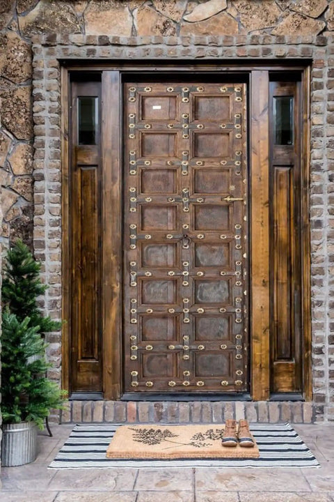 Hand Carved Rustic Authentic Doors For Interior And Exterior Use Antique Barn Door Style Custom Size 71 By 34 Inches Sliding Or Hinged Double And Single Rustic Doors No Glass No Hardware Included front view on stone wall with indoor plant