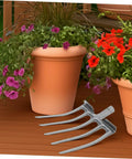 High-Performance Steel Soil Loosening Fork With Four-Tooth Design For Deep Soil Aeration shown next to potted flowers