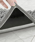 Application of Four Pack Non Slip Rug Tape For Hardwood Floors And Tiles on gray rug corner, showcasing adhesive grip