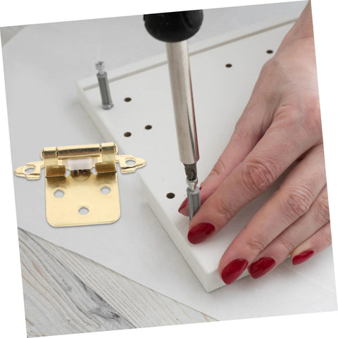 Semi-hidden spring-loaded cabinet hinge, gold-tone, installed on white cabinet; hand screws it with a screwdriver.