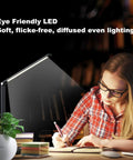 LED Desk Lamp With USB Port For Home Office And Reading, Eye Caring Light With 5 Color Modes And 5 Dimmable Levels, Touch Control And Auto Timer, Piano Style Modern Table Lamp illuminating a desk with a person writing.