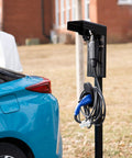 Ride-Ready Outdoor EV Charging Pedestal Housing a Tough Steel Hood Shielding Plug-In, with cables secured on solid black frame.