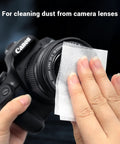 Lens cleaning tissue being used on Canon camera lens; close-up of hands wiping the lens