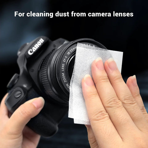 Lens cleaning tissue being used on Canon camera lens; close-up of hands wiping the lens