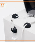 Self Adhesive Black Silicone Cable Clips Organizer Pack Of Six For USB Charging And Network Cables shown on white desk with laptop.