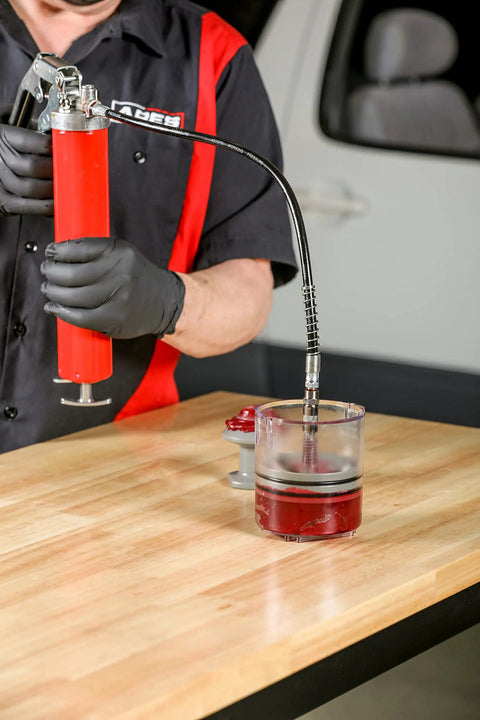 Mechanic using Deluxe Bearing Packer for quick grease flush with grease gun on a workbench; universal fit for bearings up to 3.5 inches