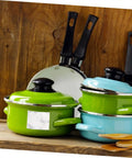 Variety of pots and pans with green and blue lids on a wooden kitchen counter