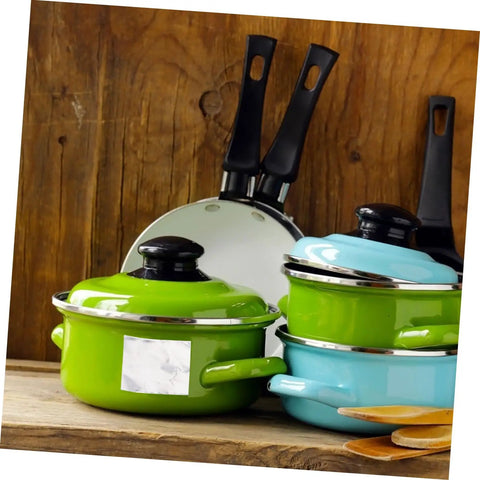 Variety of pots and pans with green and blue lids on a wooden kitchen counter