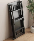 Black Folding Desk For Home Office Hustle Featuring Solid Wood Top And Heavy Duty Steel Frame Compact Portable Workstation folded against wall