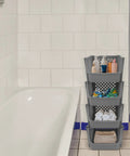 Stackable Plastic Storage Bins 4 Piece Gray Set For Home And Kitchen Open Front Design beside a bathtub, holding bathroom items.