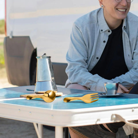 Portable Stainless Steel Picnic Cutlery Set With Organizer Reusable Fork and Spoon on a blue camping table outdoors.