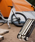 All In One Carbon Steel Bike Multi Tool For Road And Mountain Bikes With 12 Precision Tools beside a tent and bike