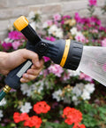 Torrent Firemans Nozzle With Quick Connect Set spraying flowers in garden, showcasing durable rubber coating and metal core.
