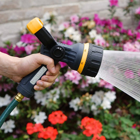 Torrent Firemans Nozzle With Quick Connect Set spraying flowers in garden, showcasing durable rubber coating and metal core.