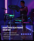 Musician playing eight-piece electric drum set with lights, featuring a 7-inch touchscreen and dual-zone mesh drum pads on stage.