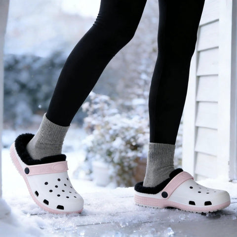 Person wearing white clogs with black fuzzy liners in snow, showcasing Two Pairs Black Fuzzy Clog Liners Warm Removable Insoles For Indoor Outdoor Wear Size 37 38 Replacement Fur Insert For Cozy Winter Steps With All Day Comfort And Cushioned Support.