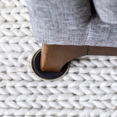 Heavy Duty Round Plastic Carpet Furniture Sliders Glide Your Couch Tables And Dressers Smooth As Butter Pads 3.5 Inches Wide under a wooden sofa leg.