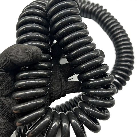 Heavy Duty Two Core Coiled Extension Cord With Smooth Retractable Stretch Design That Handles Power Draws Like A Champ And Keeps Your Setup Snappy For Zero Tangling Hassles Indoors Or Outdoors, coiled design, held in hand.