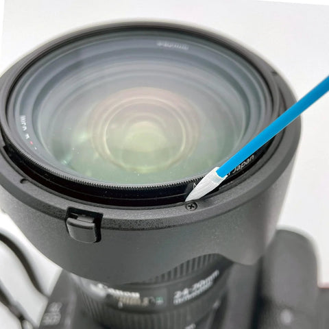 Close-up of a camera lens with a blue microfiber cleaning swab resting on the lens rim