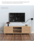 10 Foot Flat Plug Extension Cord With USB Port powering TV in living room, showcasing slim design for behind furniture.