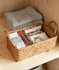 Spacious Open Top Seagrass Woven Storage Basket With Heavy Duty Handles For Kitchen Farmhouse Pantry Bathroom Towels Cosmetics And Hassle Free Daily Organization Goals with folded items inside.