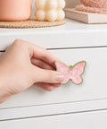 Hand holding a pink butterfly dresser knob, 2 inch zinc alloy pull, ideal for quick swaps in girl rooms.