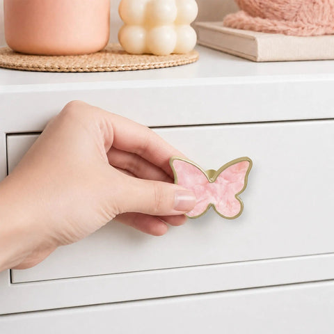 Hand holding a pink butterfly dresser knob, 2 inch zinc alloy pull, ideal for quick swaps in girl rooms.