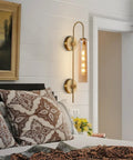 Amber Glass Wall Sconce With Brass Tube, 1 Light Modern Mid Century Vanity Fixture in bedroom setting over bed.