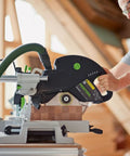 Person using KAPEX KS 120 REB Sliding Compound Miter Saw With Rail Forward Design for precise miter cutting in a workshop