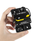 Hand holding 60 Amp Waterproof Circuit Breaker For All 12V To 48V Electric Trolling Motors MKR-27 Replacement Part Marine Grade