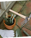 Dual Head Cultivator Garden Hoe for Lightweight Outdoor Yard Work next to garden tools in pot on brick patio