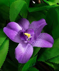 Close-up of a purple fabric flower surrounded by realistic green fabric leaves for decorative use