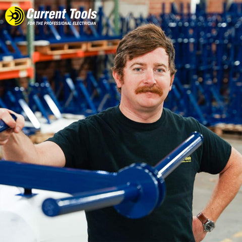 Man in workshop with blue heavy duty 12 inch hook type sheaves and rugged steel frame machinery in background, smiling