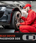 Technician in red uniform working on a rear driver passenger side wheel of a car in a garage setting.