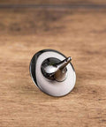 Stainless steel spinning top on a wooden surface showcasing its sleek, reflective design and precision craftsmanship.