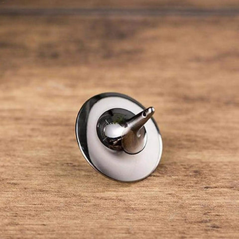 Stainless steel spinning top on a wooden surface showcasing its sleek, reflective design and precision craftsmanship.
