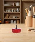 Bi Metal Hole Saw Kit For Four And A Quarter Inch with red drill bit on wooden table in workshop, surrounded by tools and shelves.
